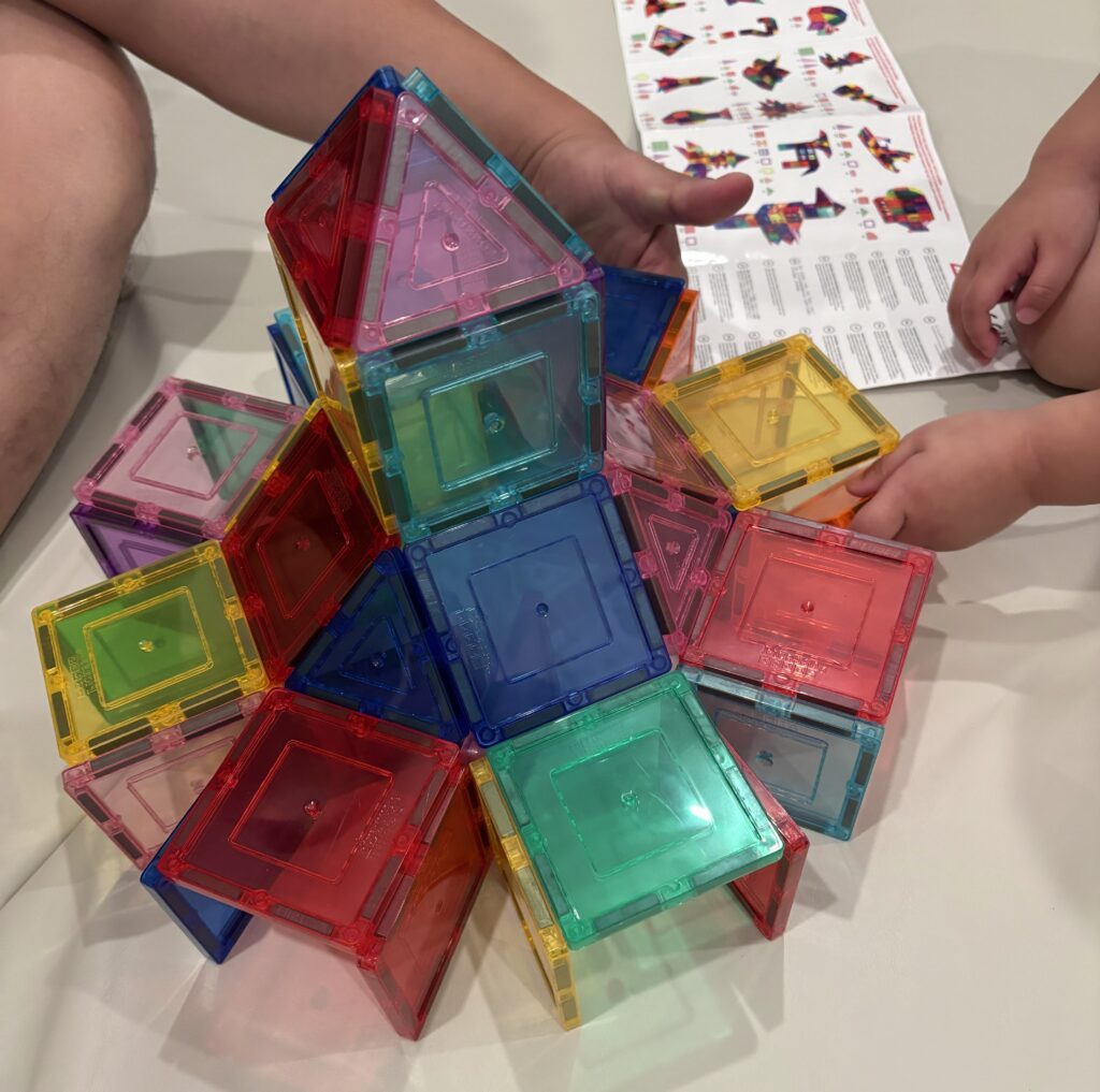 3 year old following a magnetic tile building guide